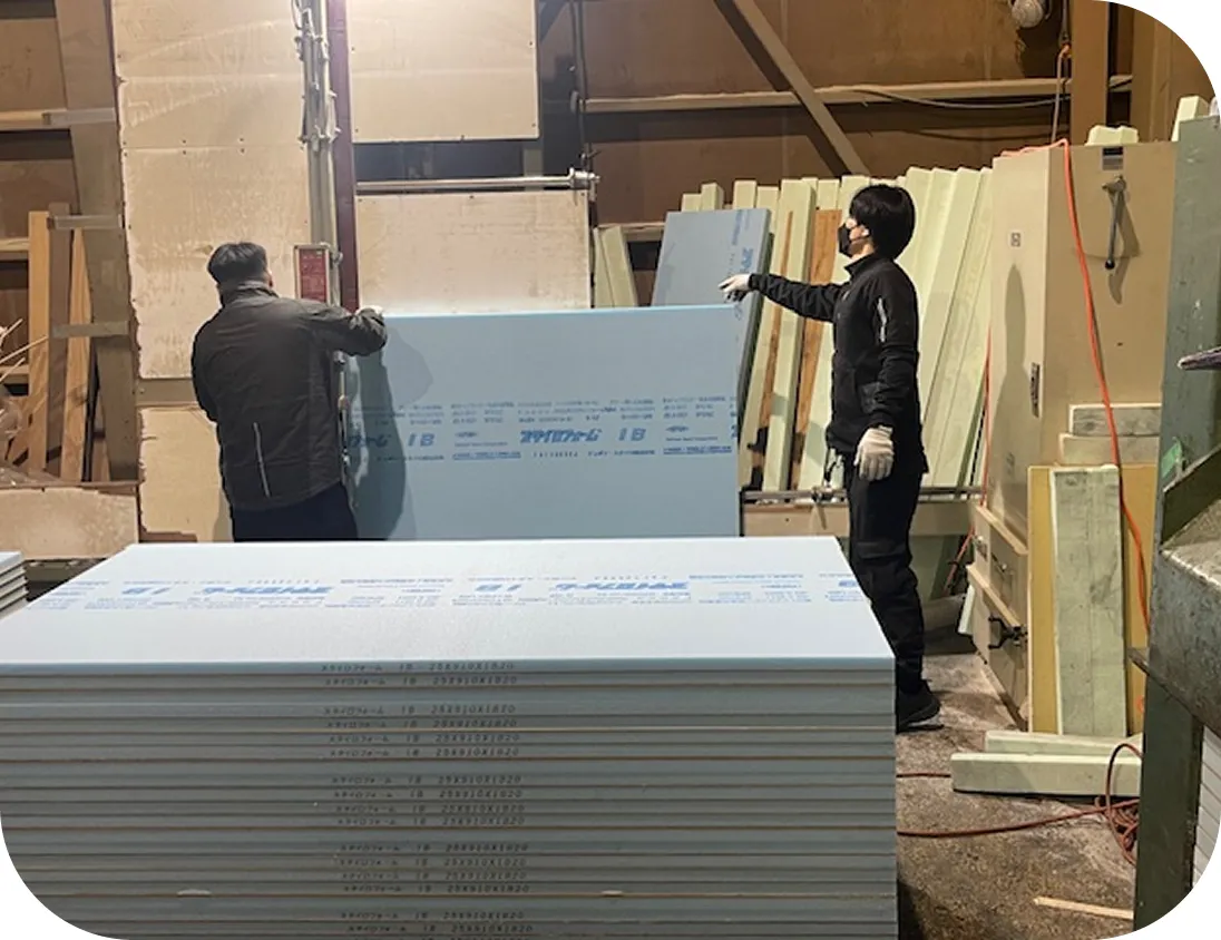 工場内で断熱材ボードを搬送・加工する作業スタッフ